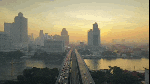 a busy highway going over a body of water with a city in the background