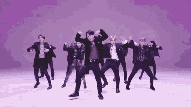 a group of men are dancing in front of a purple wall