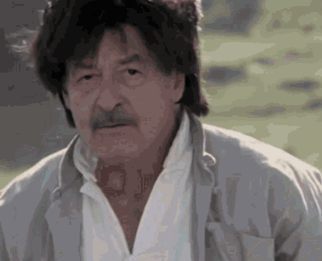a man with a mustache wearing a grey jacket and white shirt