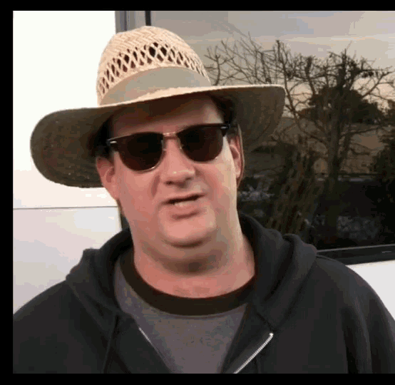a man wearing a straw hat and sunglasses looks to the side