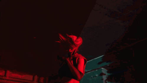 a woman is dancing in a dark room with red lights