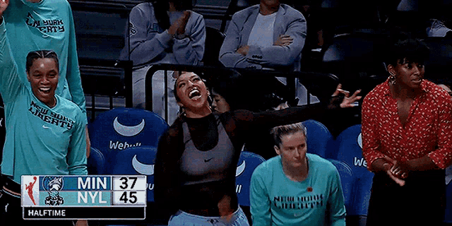 a group of women are sitting in a stadium watching a basketball game with the score 37 to 45