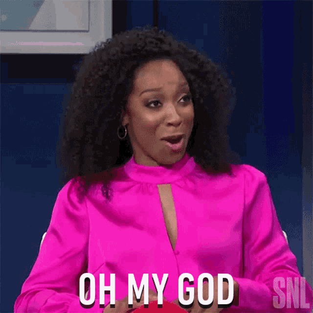 a woman in a pink shirt is sitting at a table and says oh my god .