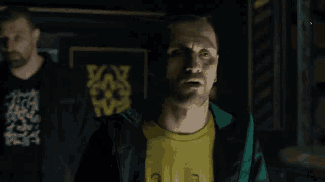 a man wearing a yellow shirt and a green jacket