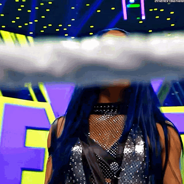 a woman with long blue hair is standing in front of a sign that says the nextbigthing