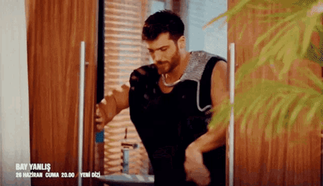 a man in a black tank top is standing in front of a door with the words bay yanlis on it
