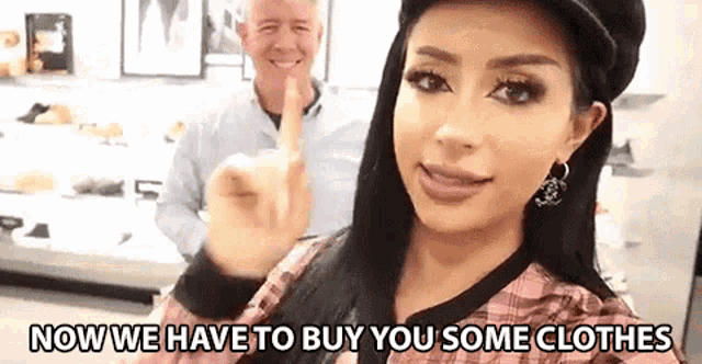 a man and a woman are standing next to each other in a store . the woman is wearing a hat and earrings .