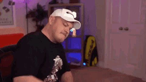 a man wearing a white hat and a black shirt is sitting in a chair in a living room .
