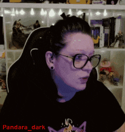 a woman wearing glasses and a t-shirt with a cat on it is sitting in a chair
