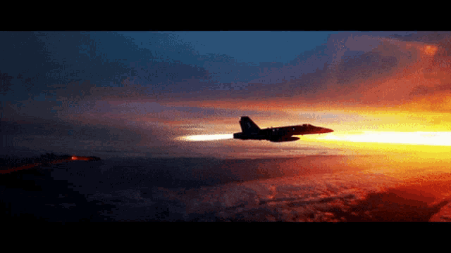 a fighter jet is flying over a cloudy sky at sunset
