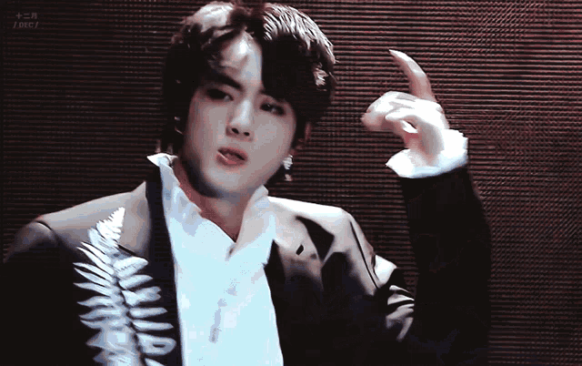 a man in a black suit and white shirt is giving a thumbs up sign