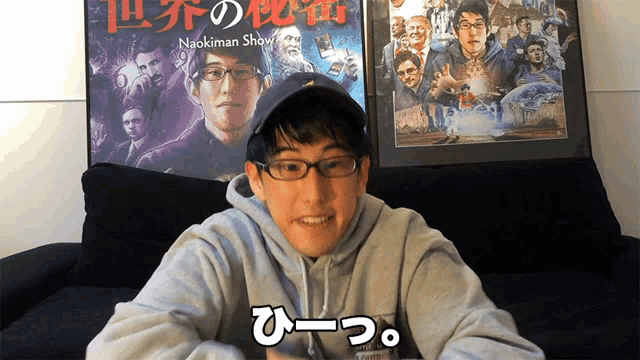 a man wearing glasses and a hat is sitting in front of a naokiman show poster