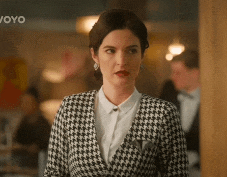a woman in a black and white houndstooth suit is standing in a restaurant