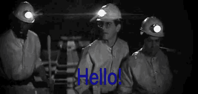 a group of men wearing hard hats are standing in a dark room with the word hello written in blue