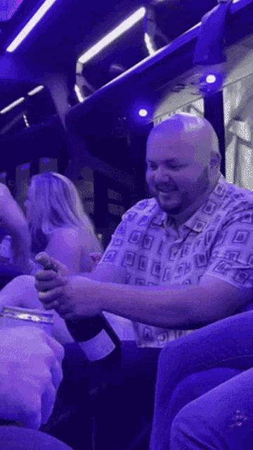 a man in a purple shirt is holding a bottle