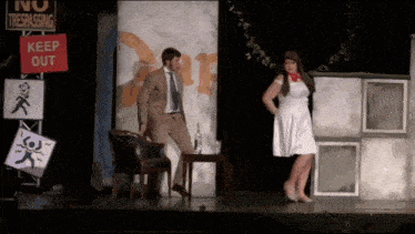 a man in a suit and tie is standing next to a woman in a white dress in front of a sign that says keep out