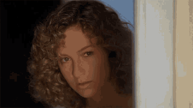 a close up of a woman with curly hair looking out a window