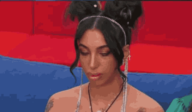 a woman wearing a headband and earrings looks at the camera