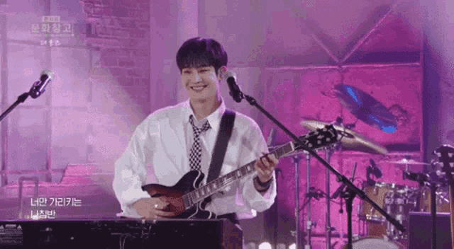 a young man is playing a guitar and singing into a microphone .