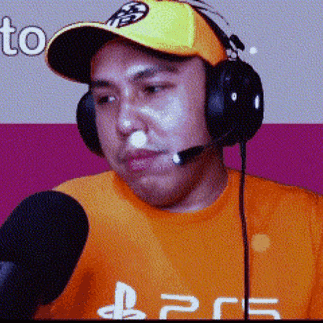a man wearing headphones and an orange shirt with the letters ps5 on it