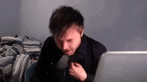 a man is sitting in front of a laptop computer eating a sandwich .