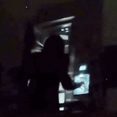 a man is standing in front of an open refrigerator in the dark .