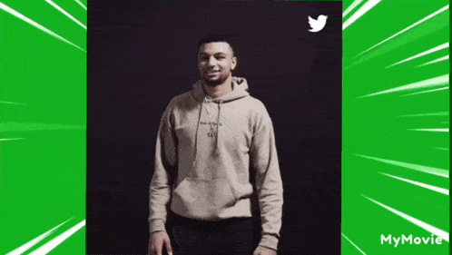 a man in a hoodie is standing in front of a twitter logo