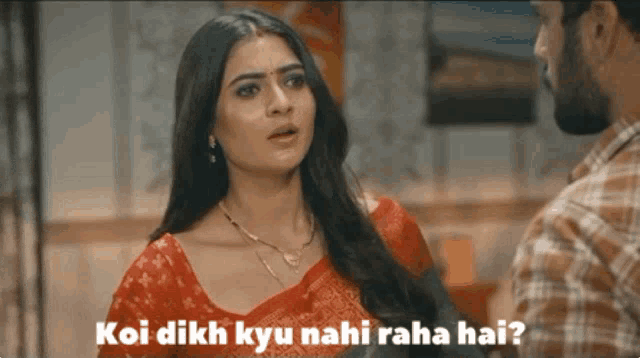 a woman in a red top is talking to a man in a plaid shirt with the words koi dikh kyu nahi raha hai
