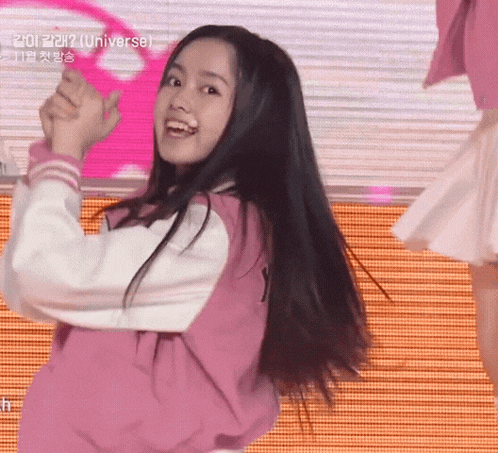 a girl in a pink jacket is smiling and holding a pink ring