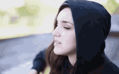 a woman wearing a black hooded jacket looks to the side