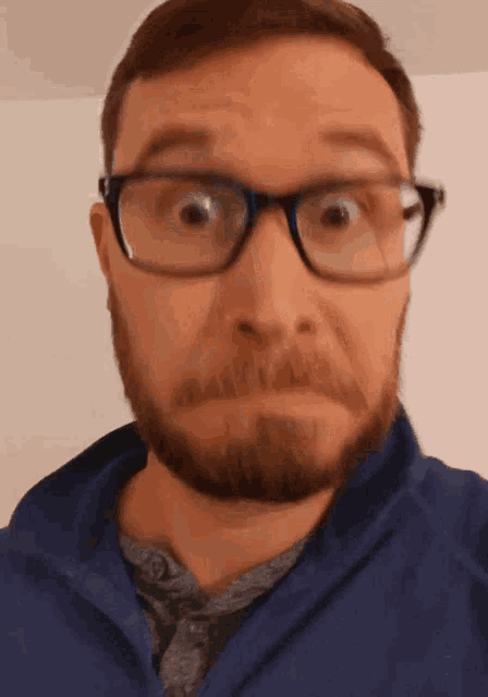 a man with a beard wearing glasses and a blue jacket