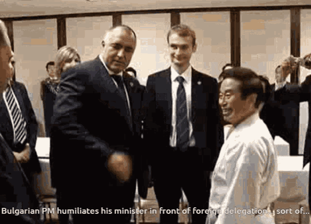 a man in a suit and tie talks to a man in a white shirt
