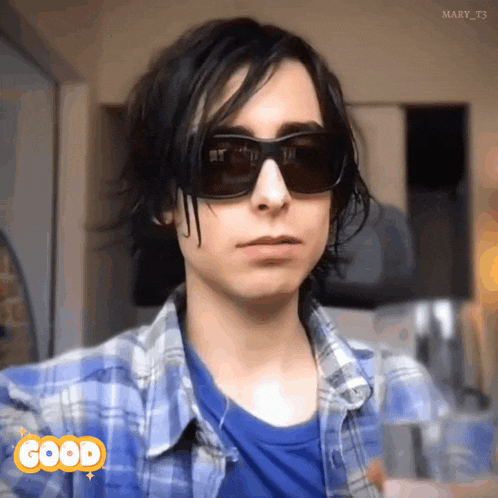 a person wearing sunglasses and a plaid shirt has a good sticker on their face