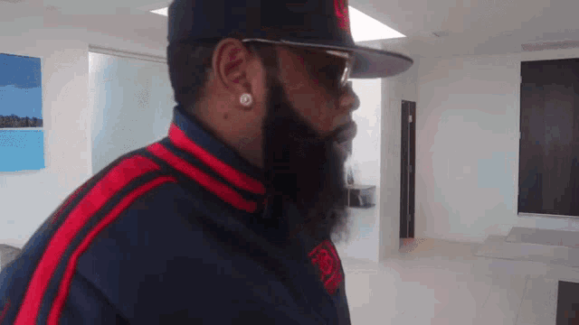 a man with a beard wearing sunglasses and a hat with the letter l on it