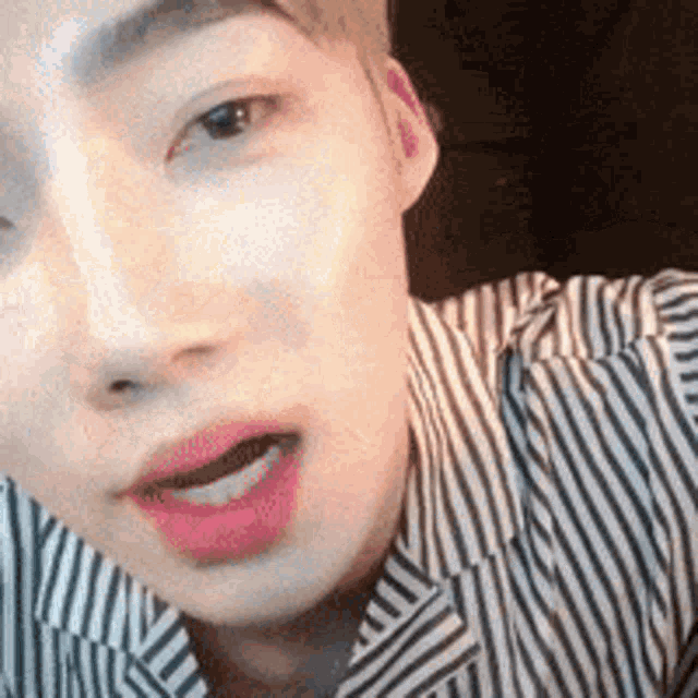 a close up of a man 's face wearing a striped shirt and lipstick .