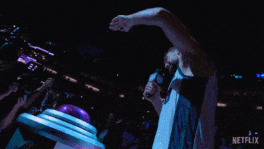 a basketball player is standing in front of a crowd holding a microphone ..