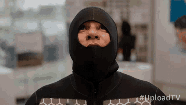 a man wearing a black hooded jacket with the hashtag uploadtv on the bottom