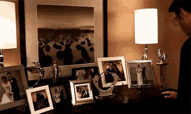 a man is standing in front of a table full of framed pictures and a trophy