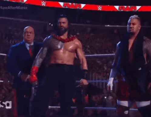 a group of men are standing in a wrestling ring holding a wrestling championship belt .