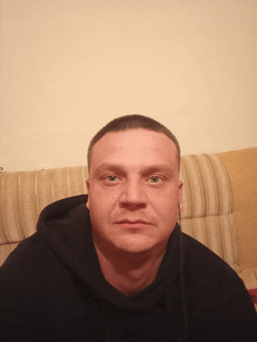 a man wearing a black hoodie looks at the camera