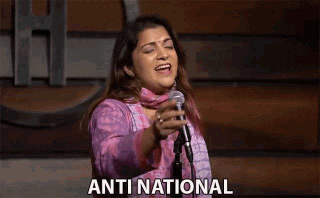 a woman singing into a microphone with the word anti national on the bottom