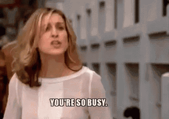 a woman in a white shirt is standing in front of a fence and saying `` you 're so busy '' .