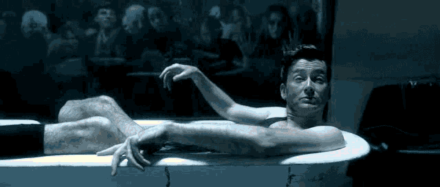 a man is laying in a bathtub with his hands on the edge