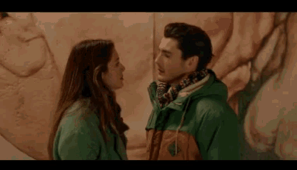 a man and a woman are looking at each other in front of a large painting .