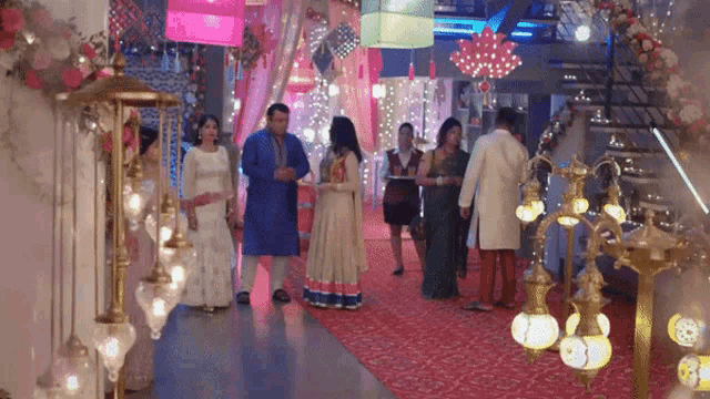 a group of people are standing in a hallway decorated with lanterns and lights .