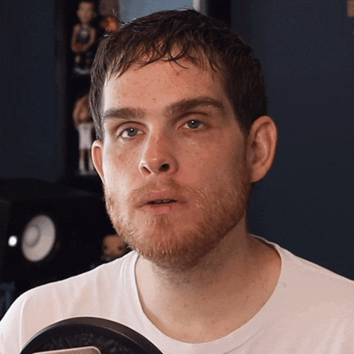 a man with a beard wearing a white shirt is looking at the camera