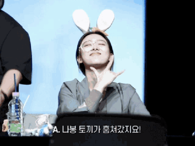 a woman wearing bunny ears and glasses is making a face