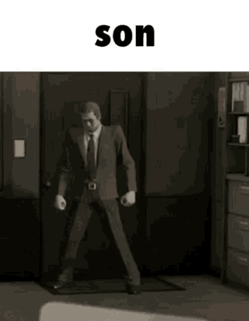 a man in a suit and tie is standing in front of a door in a room .