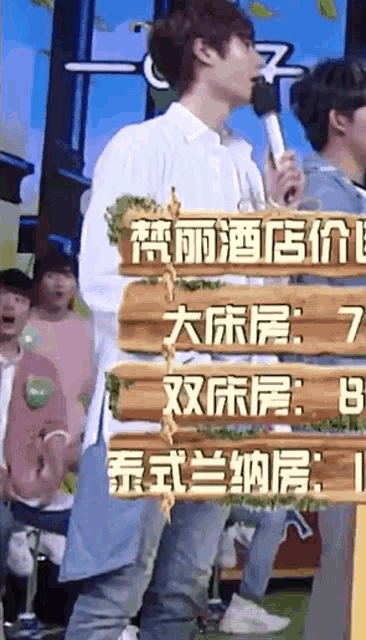 a man is holding a microphone while standing next to a sign that says 7 8 and 9