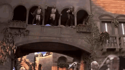 a group of people are standing on a balcony looking out over a bridge